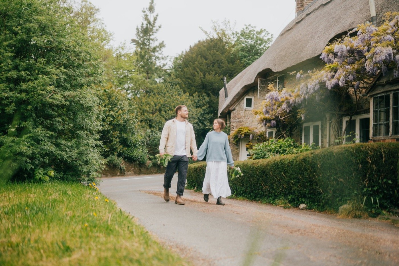 A couple walking past a thatched cottage in Godshill
