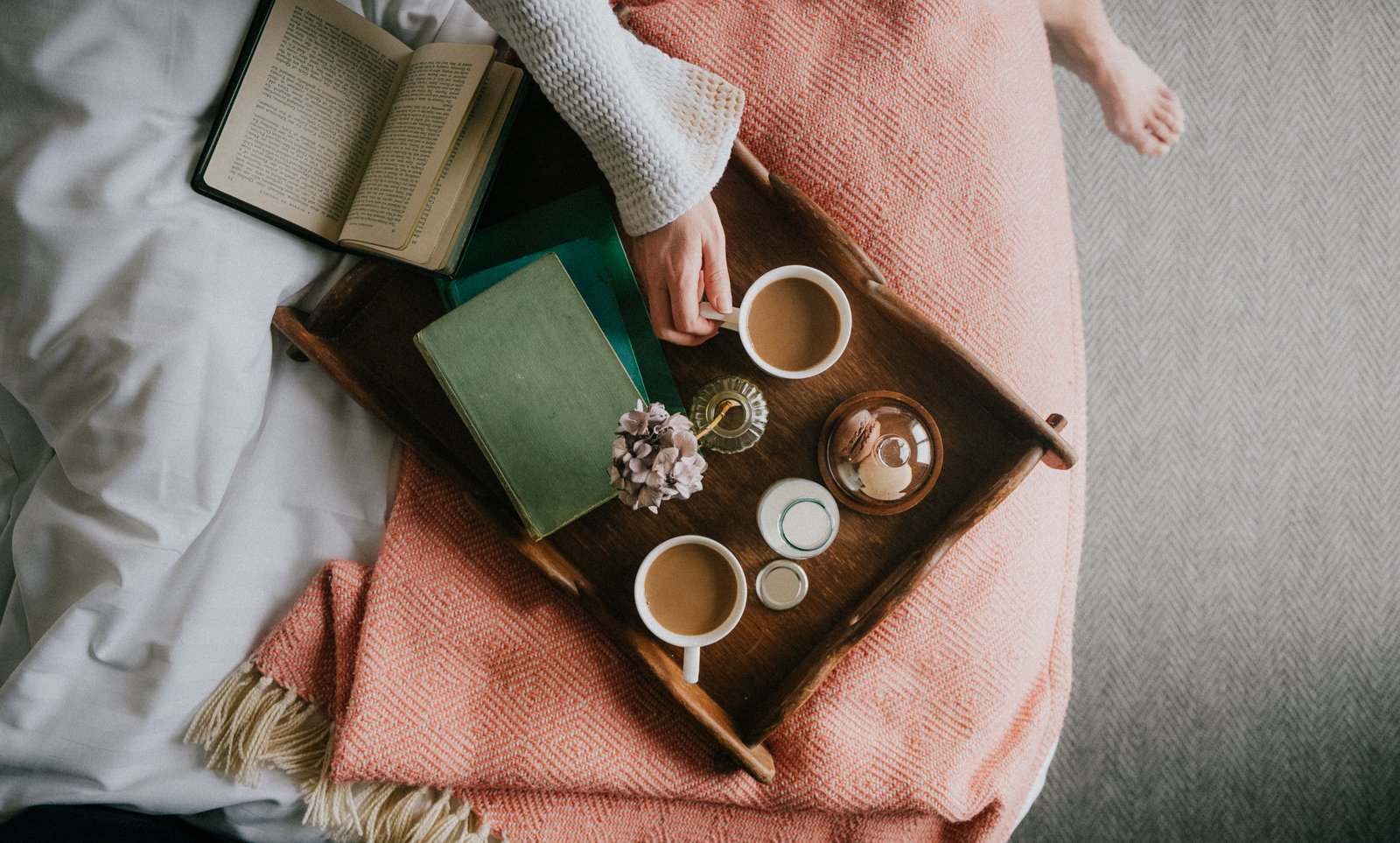 Top-down view of a hand near tea on a wooden tray