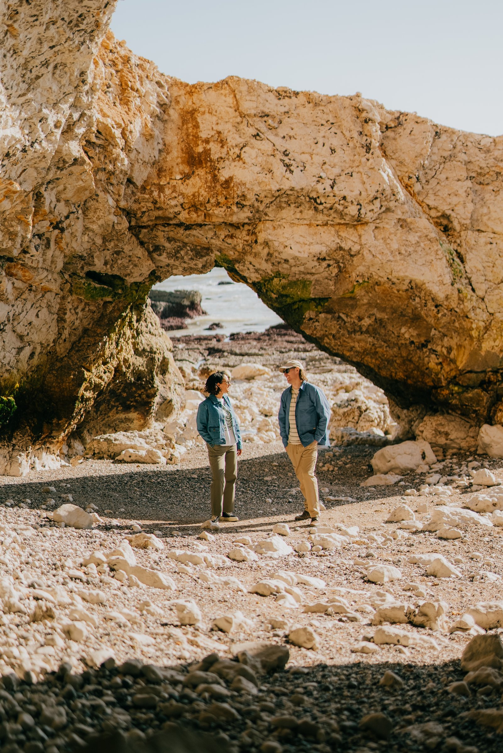 Two people beneath a massive weathered rock arch