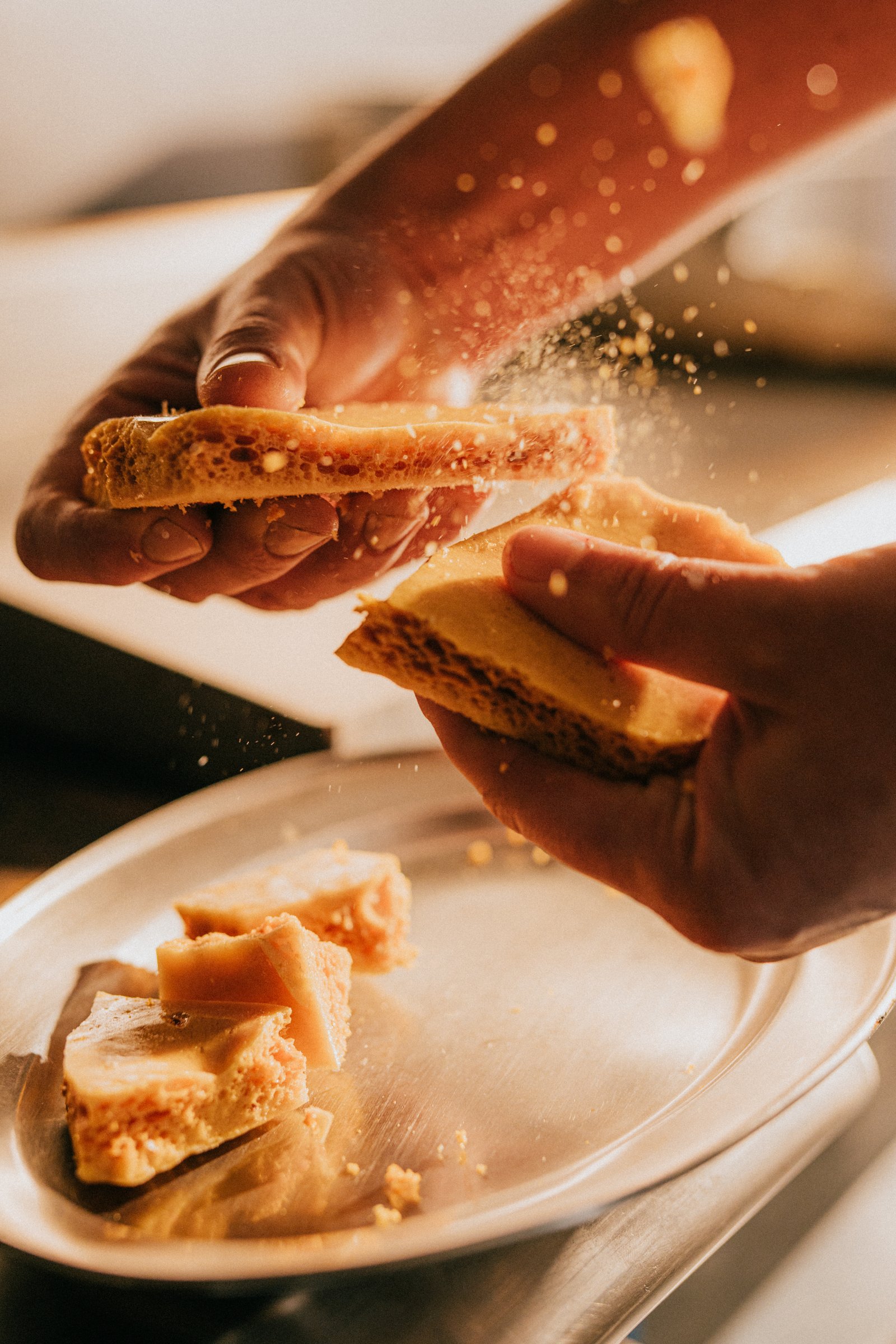 Person holding a sandwich and sprinkling sugar